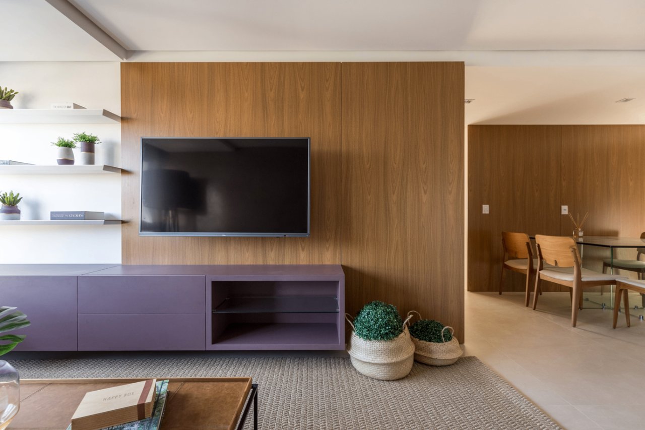 Detalhe do living do Sky com painel de madeira, TV e rack lilás