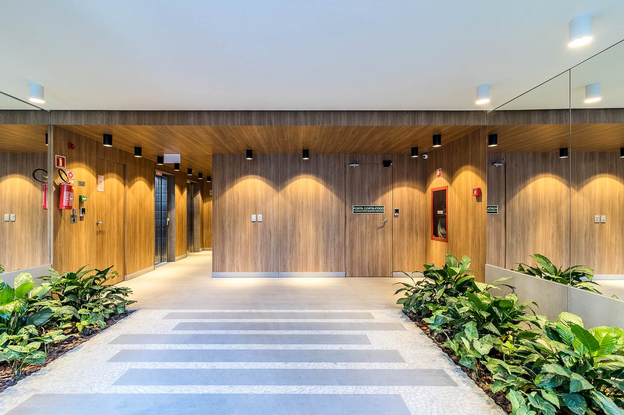 Hall decorado do Z800 com painéis em madeira, iluminação pontual e paisagismo interno