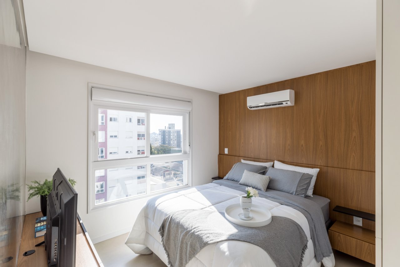 Suíte do Sky com cabeceira em madeira, ar-condicionado e vista da cidade