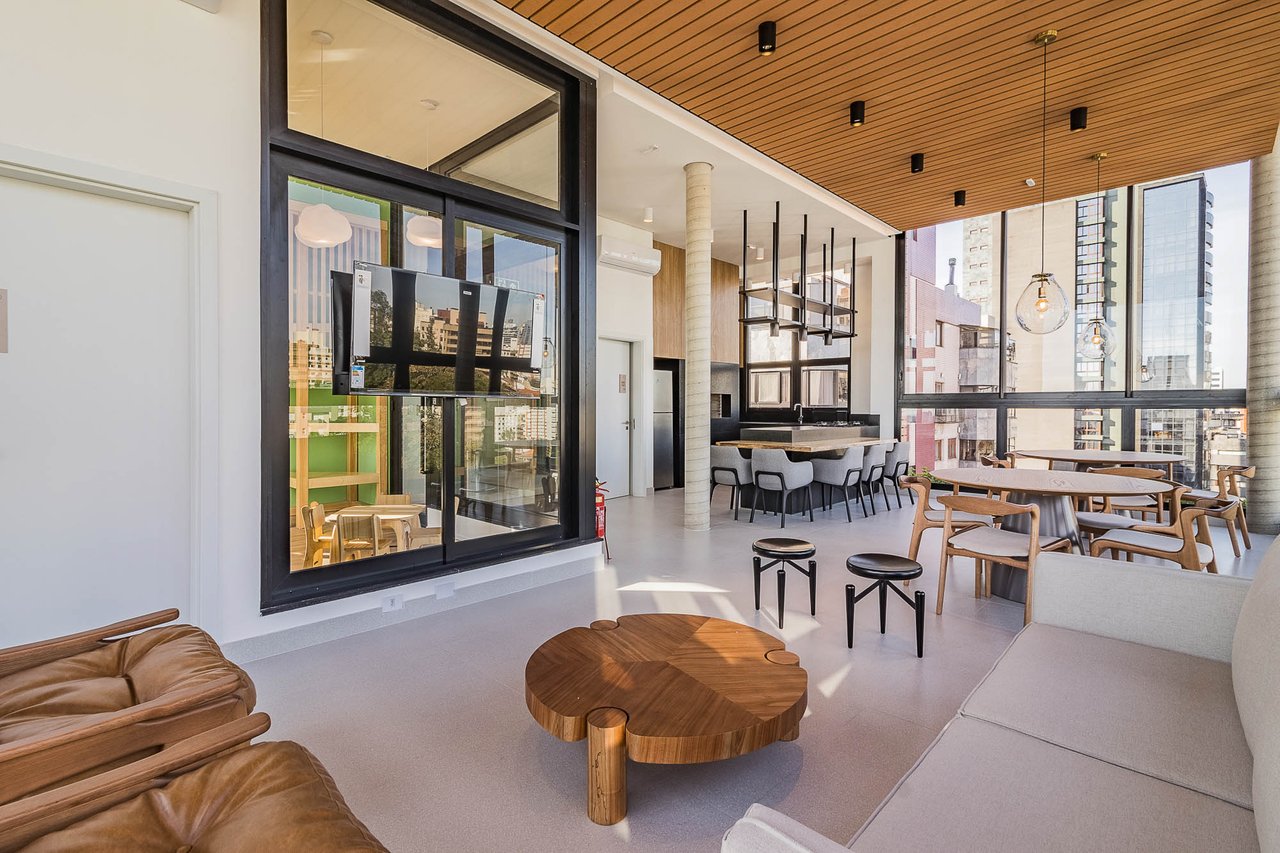 Lounge do espaço gourmet do Z800 com poltronas, sofá e vista panorâmica para a cidade