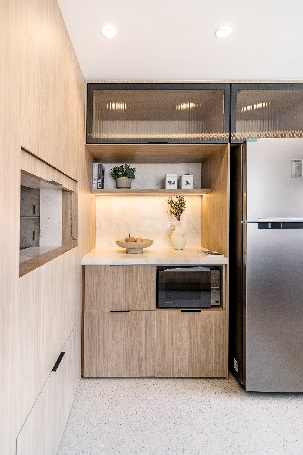 Detalhe da cozinha do Z800 com nicho iluminado, marcenaria em madeira clara e geladeira inox